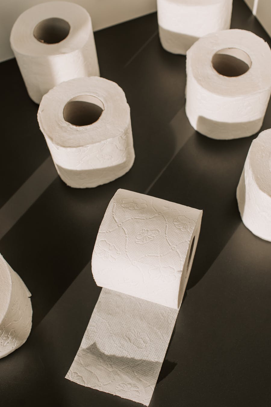 Bulk toilet rolls stacked on a dark surface